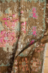 Vibrant pink blooms and recessed pile texture on a distressed vintage Oushak rug.