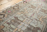 Distressed Oushak rug runner with geometric patterns, pale apricot, pink, and visible knot heads.