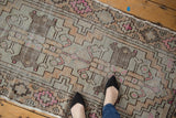 Distressed Oushak rug runner, muted rose, ivory, and silver geometric patterns, with feet.
