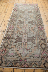 Distressed vintage Oushak runner corner with geometric stepped motifs in soft pinks and browns.