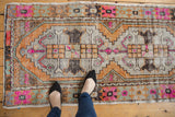 Distressed Oushak runner with geometric patterns, vibrant pink, tangerine, and grey tones.