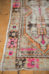 Distressed Oushak runner corner with bright pink, tangerine, and charcoal stepped geometric motifs.