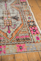 Vibrant bubblegum pink and tangerine geometric pattern on distressed Oushak rug runner's edge.