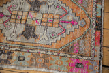 Stepped diamond geometric floral motifs on distressed Oushak rug in pink, tangerine, and silver.