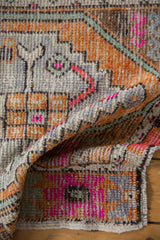 Distressed Oushak rug pile with vibrant tangerine orange and bubble gum pink geometric motifs.