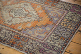 Decorative distressed Oushak runner corner with tangerine, aubergine, and silver patterns.