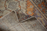 Distressed Oushak runner's tangerine, aubergine, and grey geometric pile, revealing hand-knotted back.