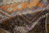 Distressed vintage Oushak runner texture with zig-zag patterns and muted orange, purple tones.