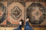 Distressed Oushak runner underfoot, showcasing geometric medallions in blush, charcoal, and navy hues.