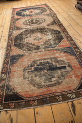 Distressed Oushak runner section showing faded gul medallion, dusty rose, charcoal, navy.