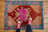 Red sneakers on a distressed Oushak rug with bubblegum pink, cherry red, and aqua hues.