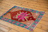 Close-up of distressed Oushak rug corner with aqua turquoise border, pink geometric motifs, and worn texture.