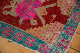 Distressed vintage Oushak rug corner, showing cherry red, pink, aqua, and exposed foundation.