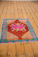 Distressed Oushak rug corner with cherry red field, aqua border, pink geometric motifs, and worn texture.