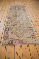 Distressed vintage Oushak runner showing blush, apricot primitive floral, and coffee brown geometric border.