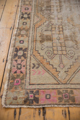 Distressed vintage Oushak rug runner with apricot, pink, brown geometric border and worn pile.