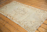 Distressed Oushak runner displaying worn ivory pile and pale tangerine meandering border.