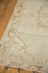 Oushak rug corner, showing distressed pile texture and meandering vine border.