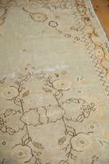 Distressed vintage Oushak rug's pile texture, ivory field, and brown meandering vine motifs.