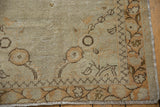 Close-up of vintage distressed Turkish Oushak rug corner, showing worn pile, ivory, tangerine, and chocolate brown vine border.