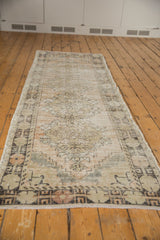 Distressed Oushak runner end, faded beige, sand, chocolate pattern, showing wear and fringe.