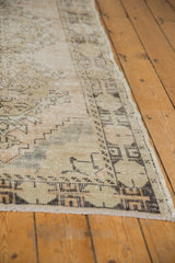 Distressed Oushak runner's textured pile and geometric border with even wear.