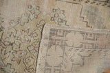 Worn beige and sand pile of a distressed Oushak rug, revealing its woven foundation.