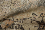 Textured pile of a distressed Oushak rug with blended beige, sand, and dark grey.