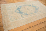 Securely finished corner of vintage Oushak rug, showing faded aqua blue and sand motifs.