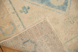 Distressed Oushak rug corner showing low aqua blue pile, fringe, and hand-knotted foundation.