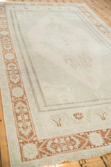 Distressed Oushak rug with a terra cotta geometric border and faded platinum field.