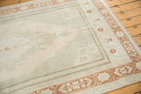 Distressed low pile, faded geometric patterns, and terra cotta border of Oushak rug.