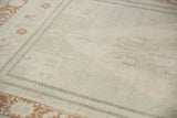 Distressed Oushak rug: pale field, low pile, subtle plant motifs, terra cotta border.
