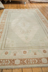 Turkish Oushak vintage carpet with distressed pile, subtle elongated medallion, and terra cotta plants.