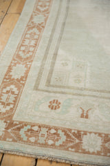Distressed vintage Oushak rug corner, showing low pile and terra cotta geometric border.