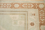 Distressed Oushak rug corner showing geometric borders and subtle germinating plant motifs.