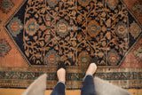 Vintage Malayer rug detail, navy field with intricate copper floral vinery and teal geometric border.