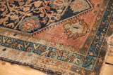 Vintage Malayer rug corner with worn blush field, navy pattern, and tattered side.