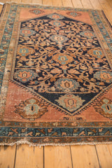 Tattered ends of the Malayer rug, with navy, copper, and celadon green borders.