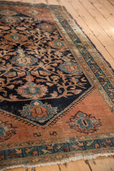 Vintage Persian Malayer rug corner, displaying intricate floral vinery, dark blush tones, and tattered fringe.