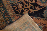 Vintage Malayer rug: folded corner shows navy floral pile with wear and hand-knotted beige foundation.