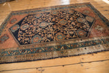 Vintage Malayer rug bottom corner detail, teal geometric border, navy floral field, visible wear.