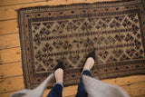 Antique Belouch rug's double column starburst floral motif with oversized leaves in beige, brown, and navy.