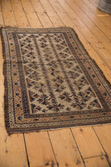 Antique Belouch rug's chocolate brown and dark navy starburst floral pattern with surface wear.