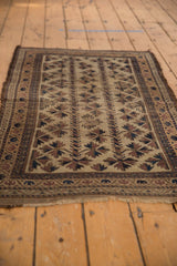 Antique Belouch rug's patterned border with rich brown and navy tones, and frayed ends.