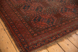 Vintage Ersari carpet corner with repeating red gul motifs, navy border, and aged pile.