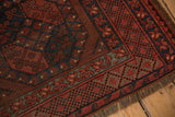 Vintage Ersari rug detail: worn red gul motifs, geometric navy borders, secure overcast fringe.
