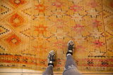 Vintage Moroccan Murat runner with saffron yellow, cochineal red starburst pattern, and visible pile wear.
