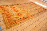 Tattered end of a vintage Murat runner, revealing worn pile and geometric border.