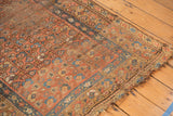 Tattered edge and worn pile of vintage Kurdish Hamadan rug with faded floral motif.
